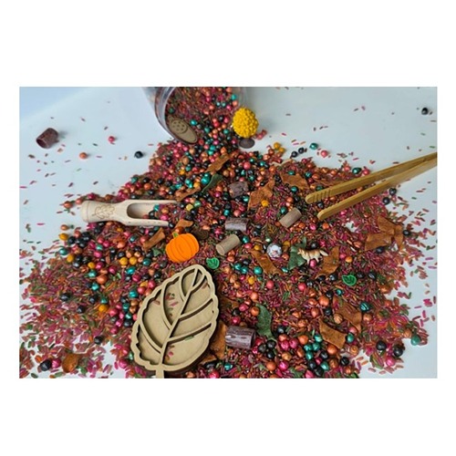 Close-up van herfst speelrijst, houten figuren, pompoenen uit de Pour and Play sensory pot voor kinderen vanaf 2 jaar